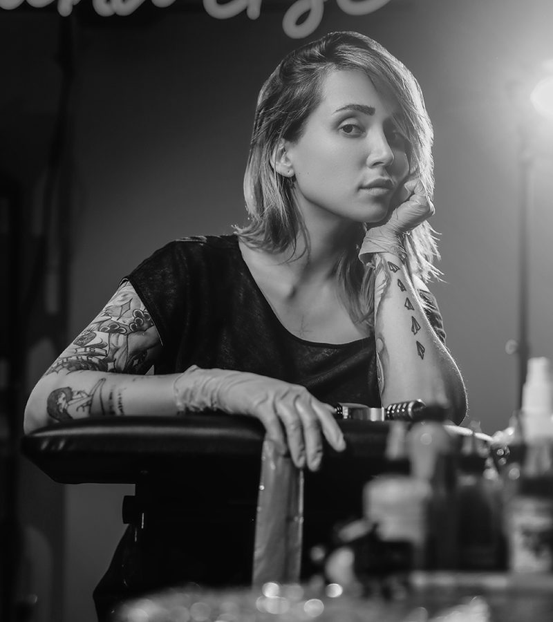 pretty woman with hand under chin sits in tattoo s D3XHZQN.jpg